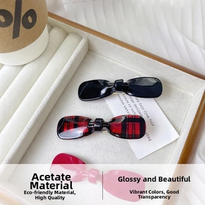 Close-up of bow hair clips in acetate material with plaid and solid color patterns