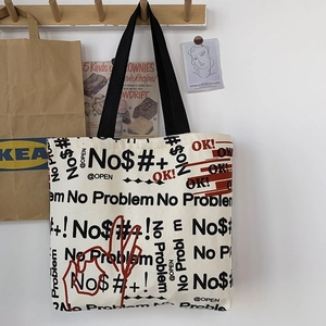 Close-up of cream canvas tote bag with black typography print hanging on a wooden hook