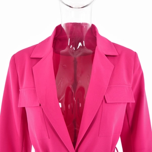 Détail d'un blazer rose à col à revers avec deux poches à rabat en tissu tissé