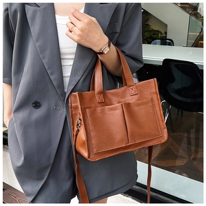 Detail of a brown textured tote bag featuring dual front pockets and versatile straps