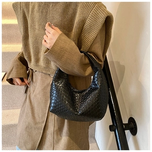 Detailed view of the black woven texture and crescent shape on this leather hobo bag