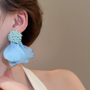 Close-up of light blue cluster flower drop earrings worn by a model in soft focus