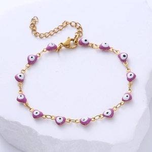 Golden stainless steel bracelet with purple heart-shaped evil eye beads on stone pedestal