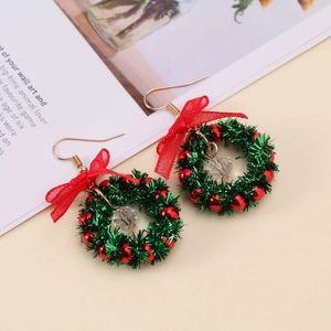 Detailed view of festive Christmas wreath earrings with red bows and green crystals