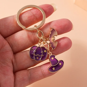 Detail of Halloween keychain with purple pumpkin, witch hat and bat charms in gold finish