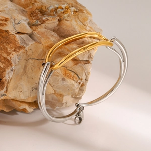 Detail of minimalist 18k two-tone stainless steel bracelet on a textured stone base
