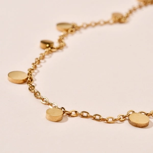 Macro shot of gold stainless steel chain necklace featuring solid round disc pendants