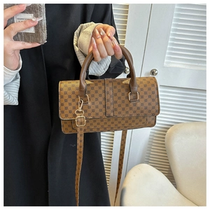 Close-up of brown litchi textured handbag with gold hardware and geometric circle pattern