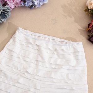 Détail du short blanc à plusieurs épaisseurs de volants et taille plissée en tissu léger