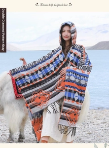 Poncho à capuche ethnique avec motifs de losanges et franges devant un paysage de lac alpin