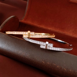 Macro detail of 18K gold and silver crisscross bracelets with pavé diamonds on leather box