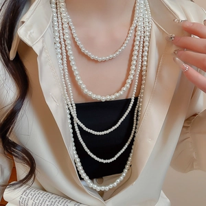Close-up of layered French vintage pearl necklace set on beige shirt with book prop