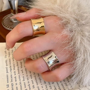 Close-up of stylish wide concave mirror rings in gold and silver on a model