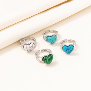 Detail of four stainless steel rings with colorful marble stones on beige fabric background