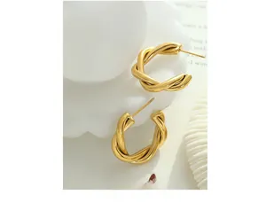 Detailed view of 18K gold plated C-shaped twisted earrings on white decor