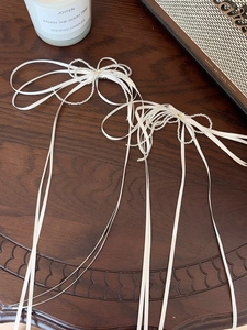 Detail of white ribbon bow hair clips with silver beaded butterfly and long tassels