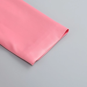 Zoom détaillé sur le tissu satin rose et les finitions de couture précises de la robe
