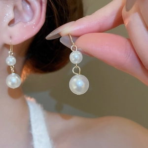 Close-up of elegant double pearl drop earrings with golden hooks and soft luster
