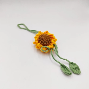Detailed view of handmade crochet sunflower charm with vibrant petals and green leaves