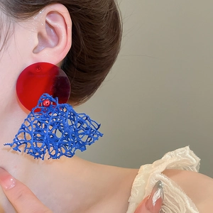 Détail de boucles d'oreilles disque rouge et résille bleue portées par un mannequin