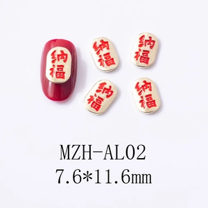 Detail view of red enamel and gold nail charms with Chinese calligraphy motifs