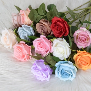 Colorful velvet artificial rose bouquet with realistic petals and leaves on soft background