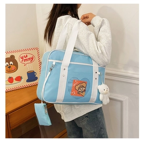 Detail of light blue JK uniform bag with heart-shaped window and plush bear charm