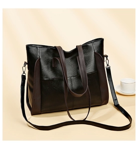 Close-up of black textured leather tote bag with brown straps and metallic hardware
