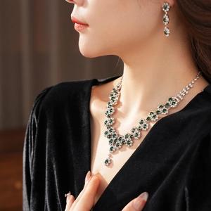 Close-up of elegant green gemstone necklace and earring set worn by a fashion model