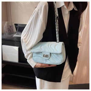 Detail of light blue quilted crossbody bag with silver chain strap and metal lock closure
