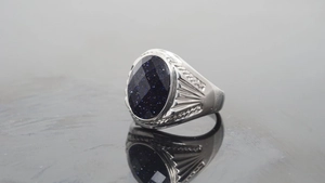 Detailed close-up of a silver ring with a sparkling blue sandstone oval gemstone