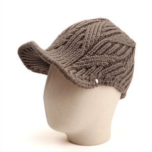 Detailed macro view of the thick cable knit texture on a dark brown winter peak hat