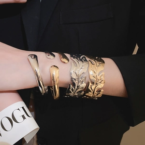 Detail of minimalist gold and silver open cuff bracelets with artistic leaf texture