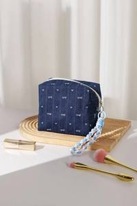 Detail of denim makeup bag with white bow embroidery and colorful braided handle