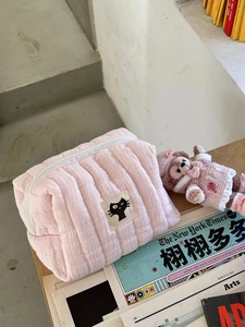 Detailed texture of pink quilted cotton makeup bag with black cartoon cat patch
