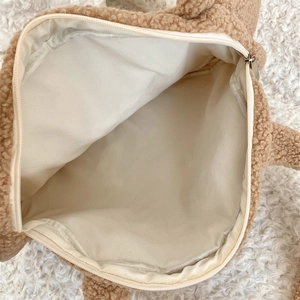 Macro view of the spacious inner lining and silver zipper of this brown plush tote bag