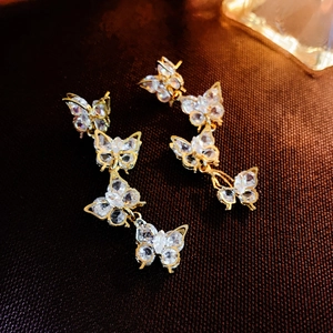 Detailed view of long gold tassel earrings with zircon-studded butterflies and glossy finish