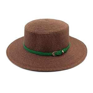 Détail d'un chapeau de paille avec boucle en cuir vert et garniture dorée élégante