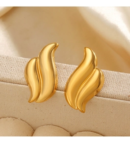 Detailed view of gold asymmetric wing earrings on a soft beige silk background