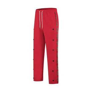Macro detail of red joggers featuring side snap buttons and plaid pattern stripe accents