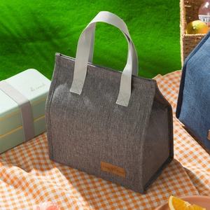 Minimalist grey insulated lunch bag with portable handles and a leather brand patch