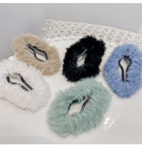 Detail of five colorful plush oval hair clips on a white plate showing soft textures