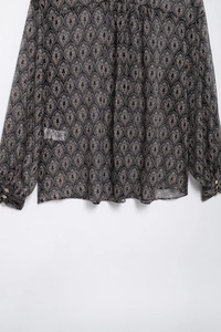 Detailansicht von schwarzem Chiffonstoff mit Paisley-Muster und goldenen Manschettenknöpfen
