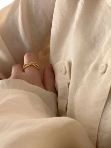 Close-up of 18K gold beaded crossover ring on hand with soft elegant lighting