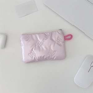 Close-up of pink quilted makeup pouch with bow pattern on a desk with laptop