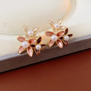 Macro shot of pink and white enamel flower stud earrings with central pearl details