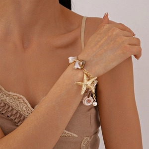 Detailed close-up of a gold starfish bracelet with natural shells and a small pearl