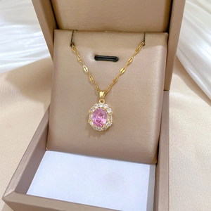 Detail shot of a pink oval gemstone necklace with a gold chain in a champagne gift box