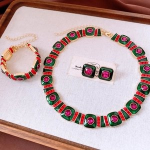 Detailed macro view of vintage gold necklace set with green enamel and pink crystals