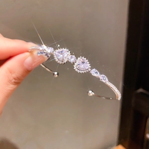 Close-up of sparkling heart and pear-shaped zircon stones on a silver open bangle